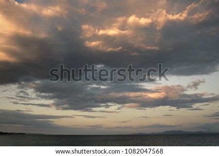 View on cloudy sky above sea surface in evening. Skyline after sunset with last rays of sun and clouds. Weather, season, weather forecast, cyclone, storm. Beautiful view. Evening sky concept.