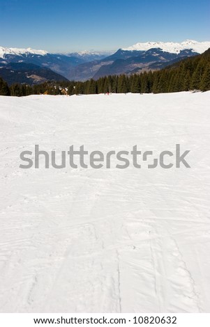 Empty green piste  with ski tracks in Meribel Valley, French Alps