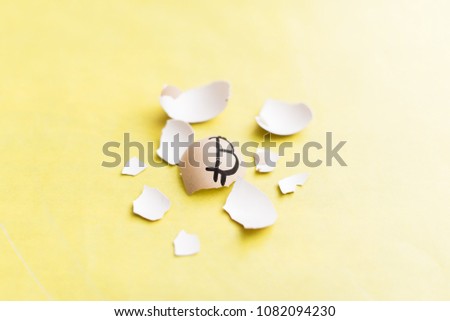 Egg with bitcoin painted on a yellow background. The concept of the collapse of the Crypto-currency