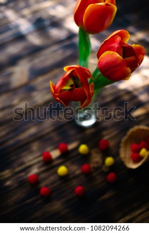 Blossoming red tulips on a wooden background with sweets.