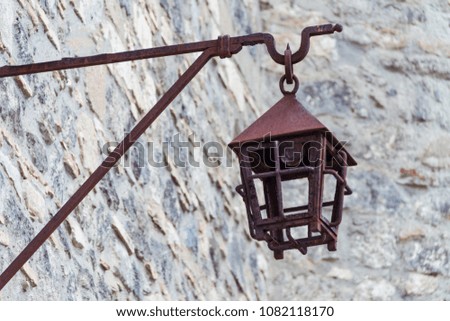 An antique iron street lamp hanging on the castle wall, a rusty metal street lamp