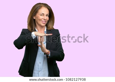 Middle age business woman serious making a time out gesture with hands