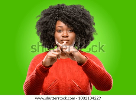 Beautiful african woman annoyed with bad attitude making stop sign with hand, saying no, expressing security, defense or restriction, maybe pushing