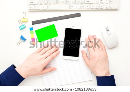 white desk, male hands, white smart phone, business card, office supplies, Notepad, keyboard, mouse, white background with copy space, for advertisement, top view
