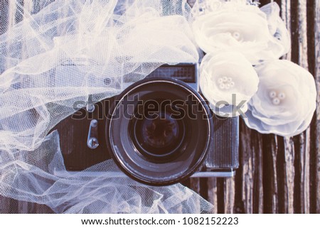 Vintage camera on a wooden texture decorated with Wedding veil and chiffon flowers. Concept wedding foto