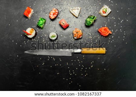 Different Sushi with Japanese knife on black stone slate background. Sushi on a table. Space for text. Top view. Sushi background. food frame