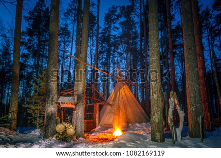 Tipe in the forest. The wigwam in the winter forest. Living in the forest. Night forest with a fire.