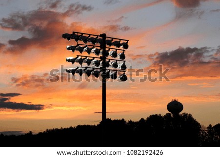 Football stadium lights silhouetted by the sunset.