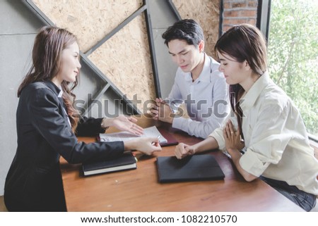 Young smiling couple about to sign a house renting agreement, happy to buy new apartment, meeting in the office with a trusted, reliable real estate agent, confident in credit