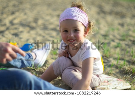 a beautiful little girl in a white t-shirt and a bandage on her head plays in nature