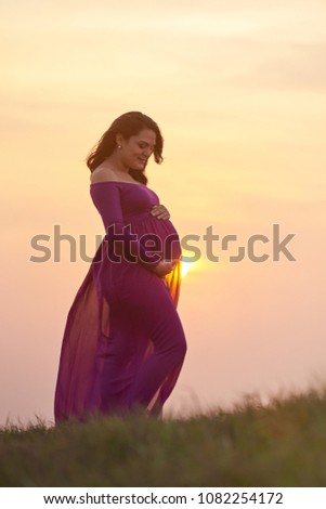 Pregnant woman on sunset light. Young woman hold pregnant belly