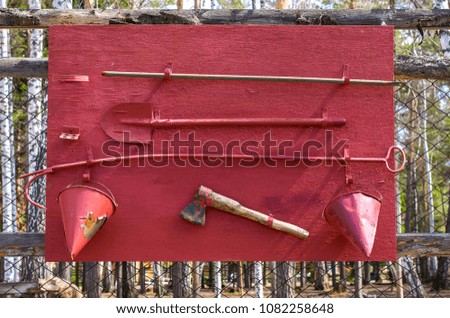 red fire shield with a shovel, buckets, axe on the fence fencing nature object