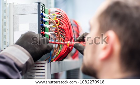 Closeup of electrician engineer works with electric cable wires of fuse switch box. Electrical equipment Royalty-Free Stock Photo #1082270918