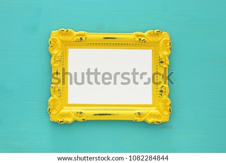 Vintage blank yellow photo frame over mint background. Ready for photography montage. Top view from above