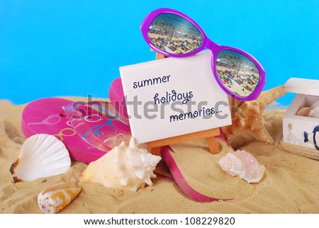 beach still life with greetings text written on easel ,flip-flop,seashells and seaside reflected in  sunglasses