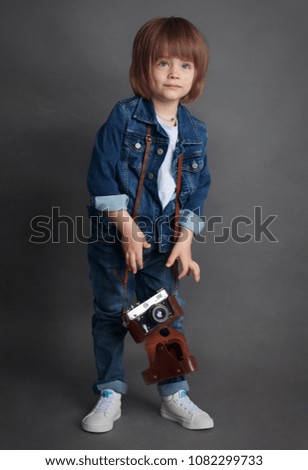 Full-length portrait of a awesome beautiful little boy with a vintage film camera