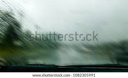 Heavy rains summer months of April due to summer storms. Abstract blur of rain drops falling on the windscreen.