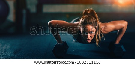 Cross training. Young woman exercising with dumbbells Royalty-Free Stock Photo #1082311118