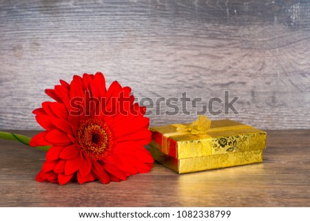 red gerbera flower with gift box on wooden table