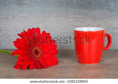 red gerbera and cup on wooden table, good morning concept