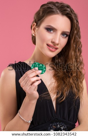 Portrait of a beautiful young woman with poker chips on pink background