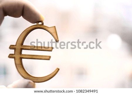 one Hand holding wooden euro money sign on blurred bokeh background. empty copy space for inscription. 