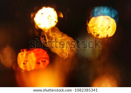The blurred light of the lamps, visible through the wet glass of the car. Out of focus.