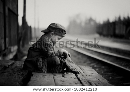Little sad boy, traveler kid waiting alone, retro picture with grain, black and white shot.