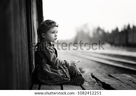 Little sad boy, traveler kid waiting alone, retro picture with grain, black and white shot.