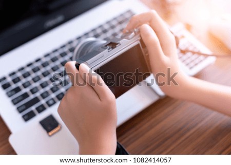 Modern Digital camera  in boy hand ,Camera Photographer workplace , Camera, Laptop ,calculations ,  on wooden desk. concept of photographer work station
