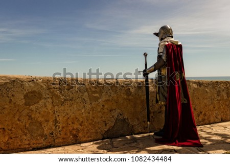 Medieval Templar soldier watches the coastline from the wall Royalty-Free Stock Photo #1082434484