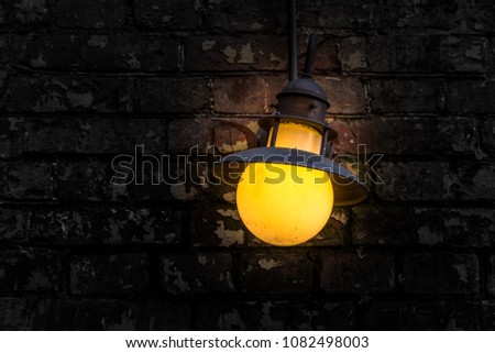 Burning old flashlight on a dark background of a brick wall close-up