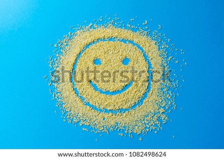 Happy emoji smile on a blue background. Smiley from yellow sugar grains. Stock image.