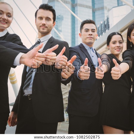 Group of successful professional business team with thumbs up outdoor with office building background