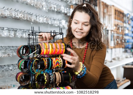 Young girl seller offering colored bracelets on the stand 
