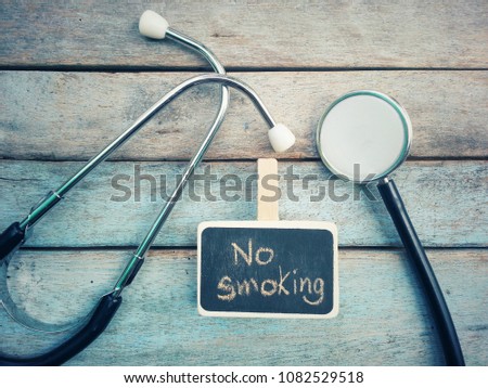 close up chalkboard with no smoking text and stethoscope on old wood table, world no tobacco day concept, top view, vintage tone