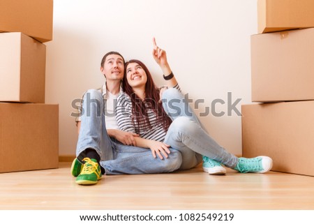 man and woman sitting on floor among cardboard boxes