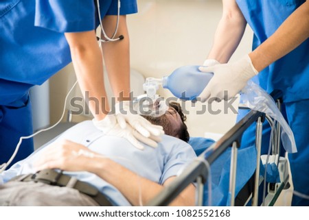 Hands of doctors giving cardiac massage and resuscitation to a male patient in the emergency room Royalty-Free Stock Photo #1082552168