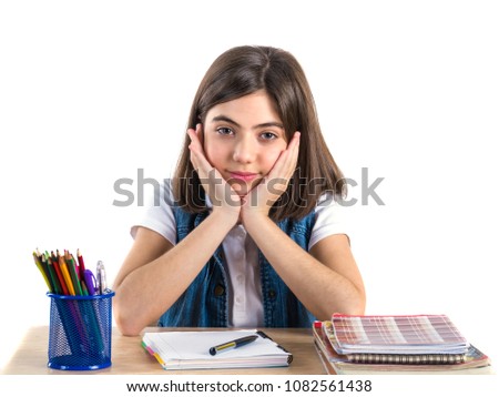 A beautiful school girl sits at the desk and thinking. White background.
