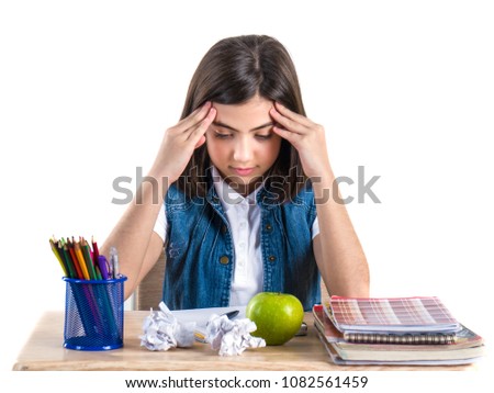 A beautiful school girl sits at the desk with apple and thinking. White background.
