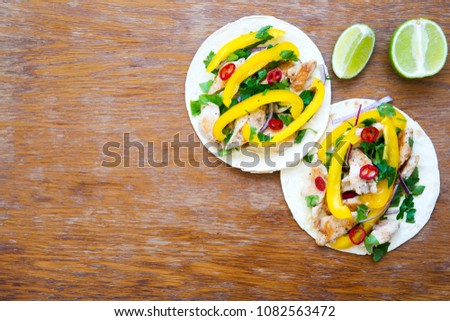 Two tacos with grilled chicken fillet, fresh vegetables, lime on rustic wooden background. Top view, from above. Flat lay. Copy space.