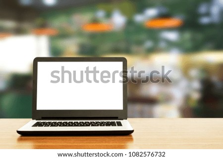 Laptop with blank screen on table with cafe background