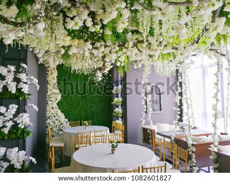 White floral wedding theme decorated with a lot of white flowers and table and sofa with grey wall Royalty-Free Stock Photo #1082601827