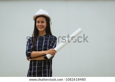 beautiful Asia woman,teen girl,student holding a roll of paper work  wear white helmet posing,make gestures with fun  and happy.engineer working with happy.