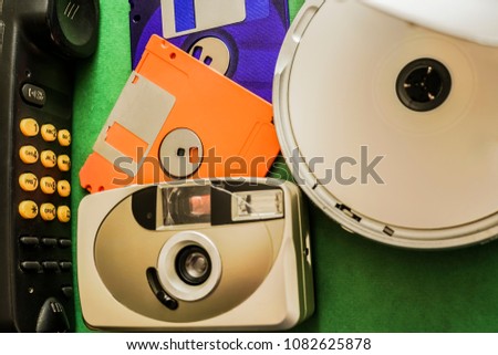 old radio telephone, vintage analog photo camera, two retro diskette and CD player - obsolete, outdated objects lie on green background 