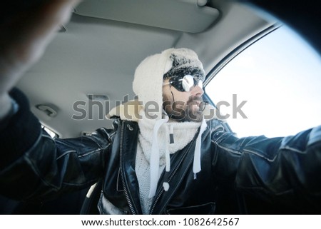 driver of the car in winter clothes, man behind the wheel, a winter journey on car,  brutal man with  beard on the car,  professional traveler