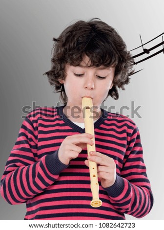 Cute child with pink jersey playing a flute with a grey background
