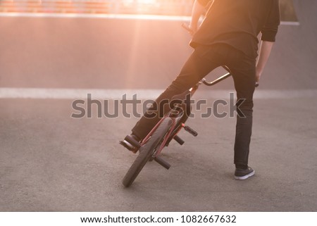 Bmx rider performs tricks on a bmx bike in a skate park on the background of the sunset. Bmx Concept. Copyspace.