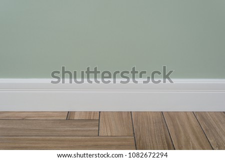Light green matte wall, white baseboard Royalty-Free Stock Photo #1082672294