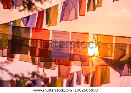 'Selective focus' Vew of some colorful Tibetan flags illuminated by a beautiful sunset in the summit of a Himalayan mountain. Royalty-Free Stock Photo #1082686850